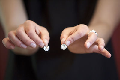 Midsection of woman holding diamond earrings