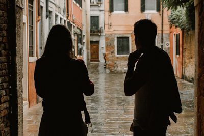 Rear view of silhouette people standing against buildings in city