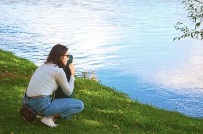 Side view of woman sitting by lake