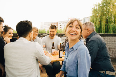 Portrait of smiling female sitting with friends and enjoying at social gathering