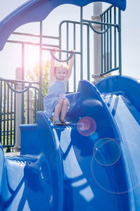 Full length of girl sitting against blue sky