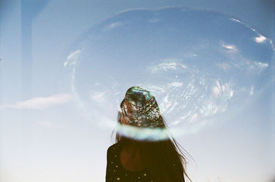 Low angle view of woman holding glass against sky