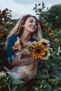 Young woman holding dog and flowers