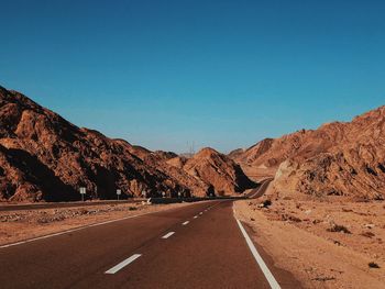 Road amidst mountains against clear blue sky