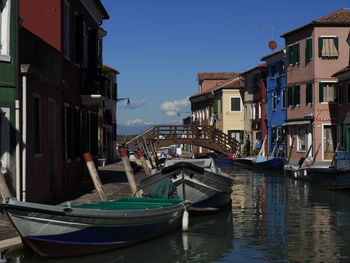 Boats moored in canal amidst buildings against sky