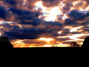 Silhouette of trees against cloudy sky