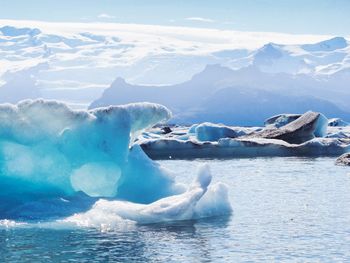 Scenic view of sea and snowcapped mountains against sky