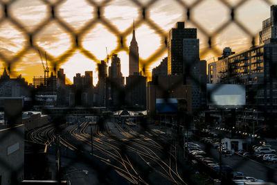 Empty train tracks glowing from behind a fence at sunset in new york.