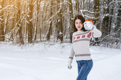 Portrait of woman holding chainsaw on snow field