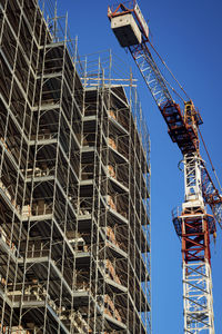 Low angle view of construction site against clear blue sky