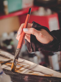 Close-up of female painter hand holding paintbrush while painting on canvas