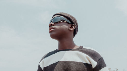 Low angle view of young man wearing sunglasses against sky