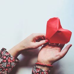 Close-up of woman holding red heart over white background