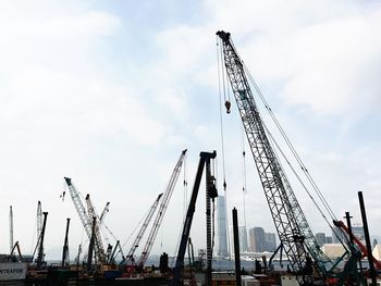 Low angle view of crane against cloudy sky