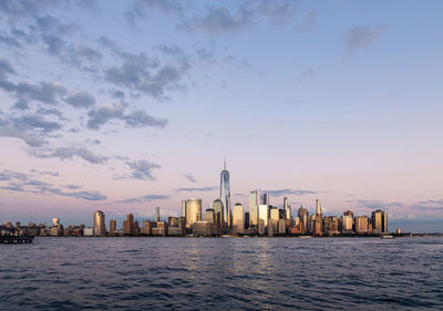 Buildings by sea against sky during sunset