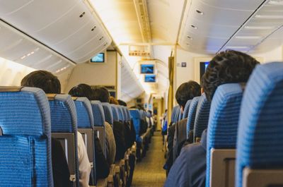 Rear view of passengers sitting in airplane