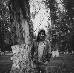 Portrait of smiling young woman standing against trees