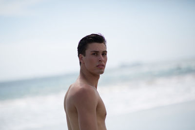 Portrait of handsome young man standing at beach