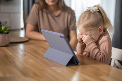 Young woman using digital tablet while sitting on table