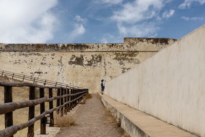 Rear view of woman walking on steps against sky