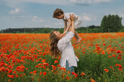 Happy mother's day. little boy and mother is playing in a beautiful field of red poppies