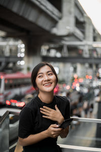 Portrait of smiling young woman using mobile phone in bus