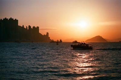 Silhouette boat sailing on sea against clear sky during sunset