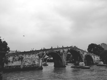 Bridge over river against sky in city