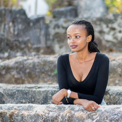 Thoughtful young woman standing by retaining wall