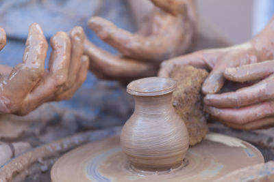 Cropped image of people making mud pots