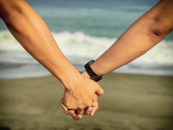 Cropped image of hands holding water on beach