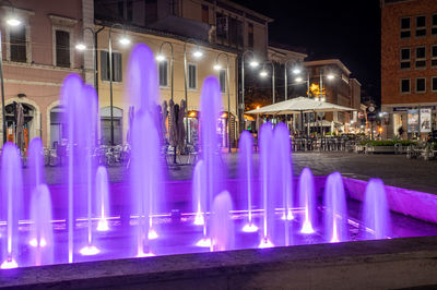 Illuminated buildings by street in city at night