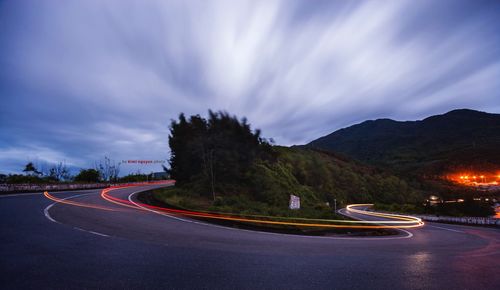 Light trails on road against sky at night