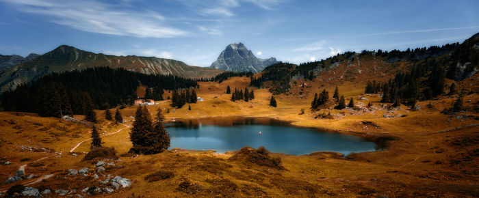 Scenic view of lake by mountains against sky