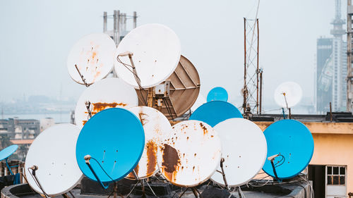 Low angle view of telephone pole against buildings in city against sky
