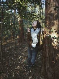 Woman looking up while standing in forest