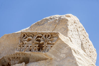 Low angle view of rock against clear blue sky