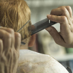 Cropped image of boy getting haircut at salon