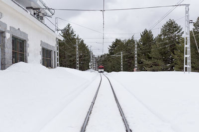 Snow covered railroad tracks by trees during winter