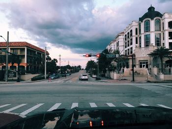 View of city street against cloudy sky