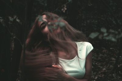 Woman with long hair standing against trees in forest