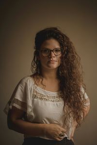 Portrait of young woman standing against gray background