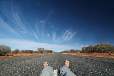 Low section of man on road against sky