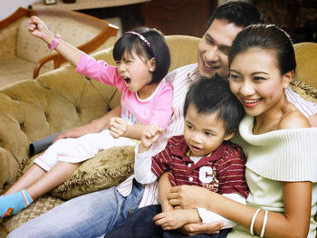 Cheerful family sitting on sofa at home