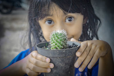 Close-up portrait of cute girl holding potted plant