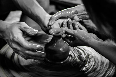 Cropped hands of people working on pottery wheel