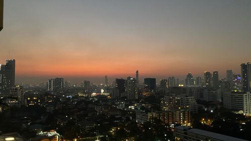 Illuminated buildings in city against sky during sunset