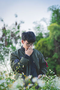 Young man standing by flowering plants