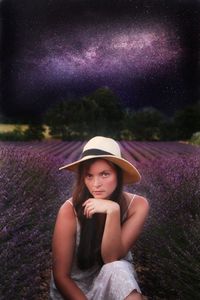 Portrait of beautiful young woman with purple flower in field