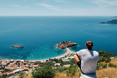 Rear view of man looking at sea against sky